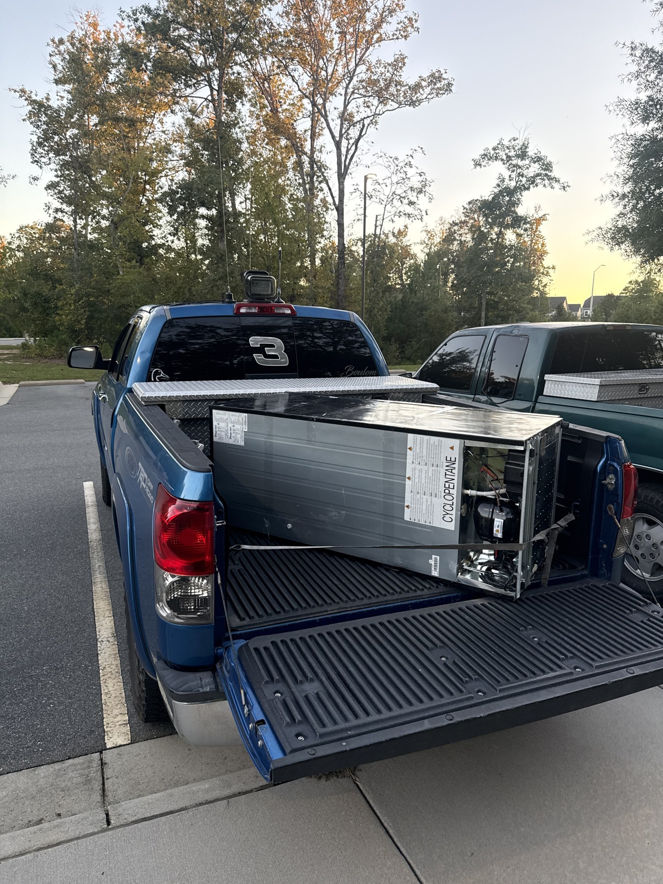 Pickup truck carrying a large appliance in its bed