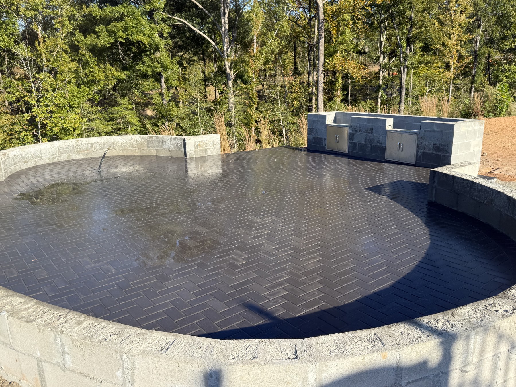 Dark paver patio bordered by a curved masonry seating wall