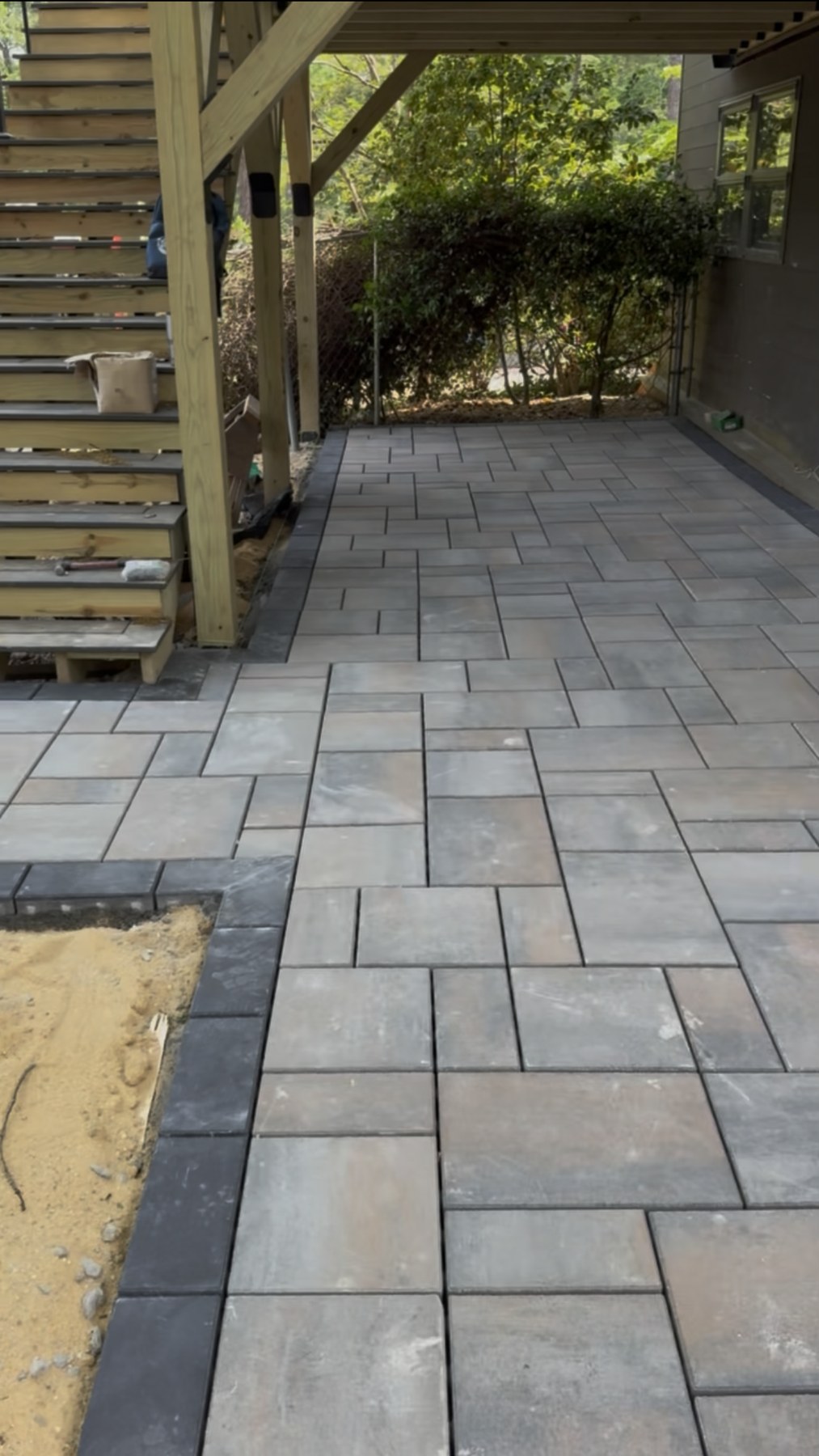 Gray rectangular pavers beneath an elevated wooden deck