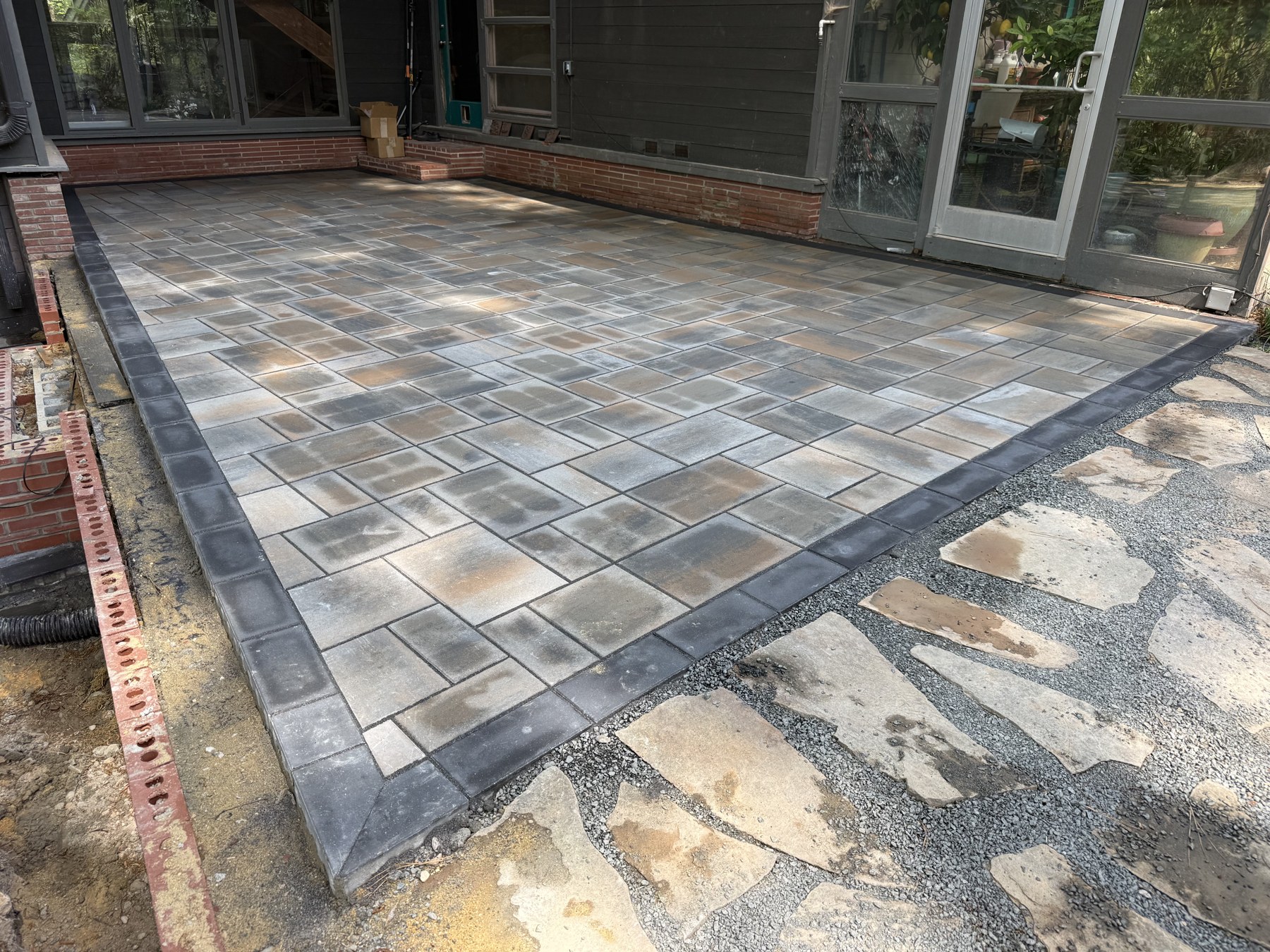 Gray paver patio beside a screened porch